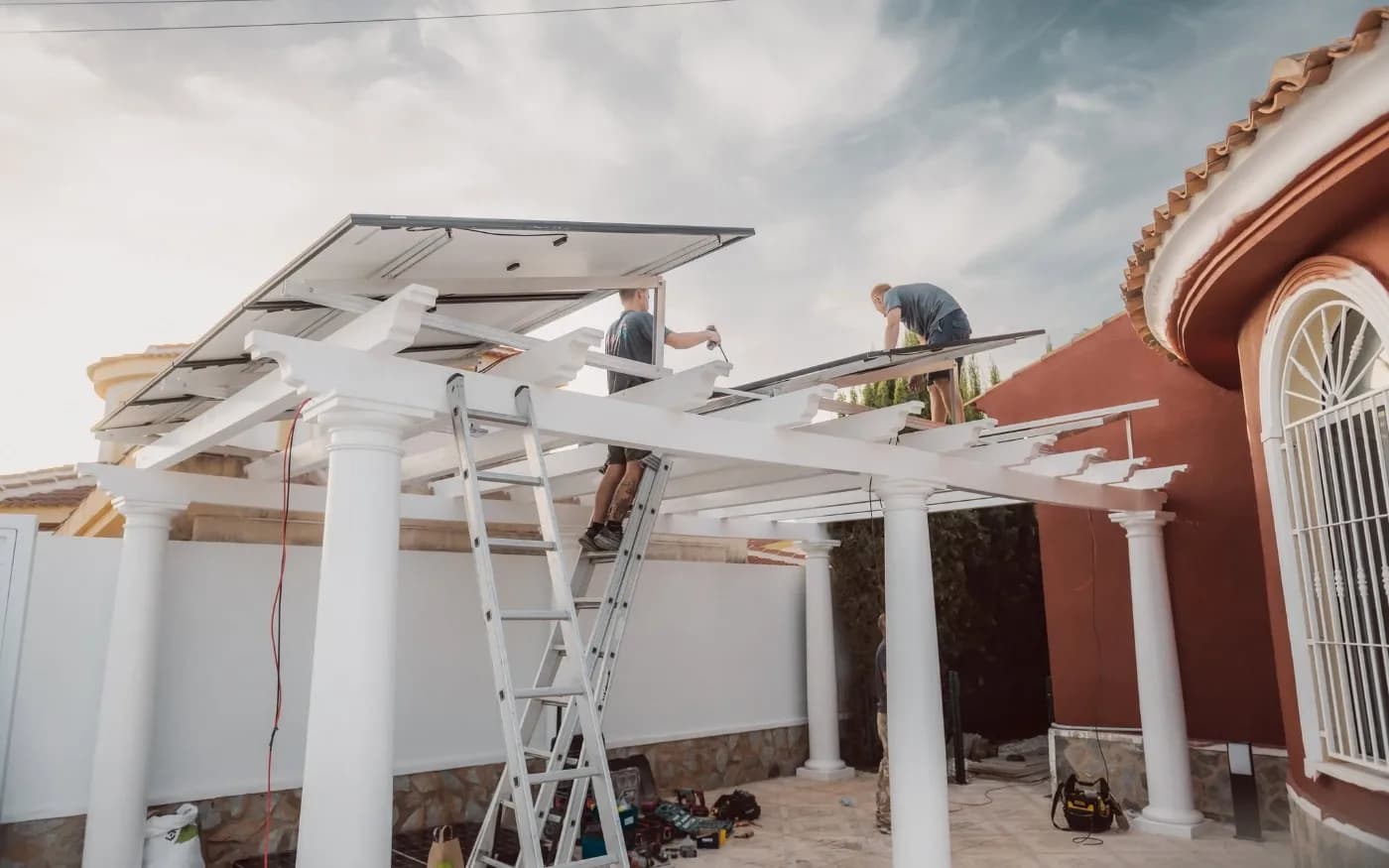 Panels being mounted on angled metal supports above the pergola beams.