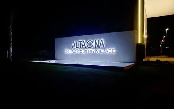 Illuminated Altaona Golf & Country Village sign and exterior lighting at night.