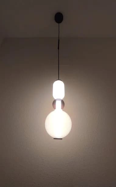 Close-up of the illuminated bedside pendant shown in the room view.