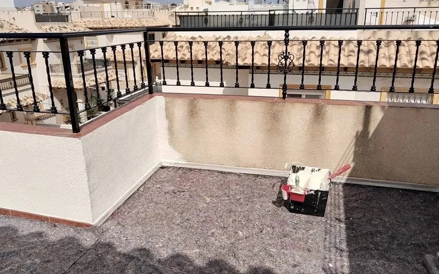 Roof terrace parapet partly painted, with floor protected by dust sheets.