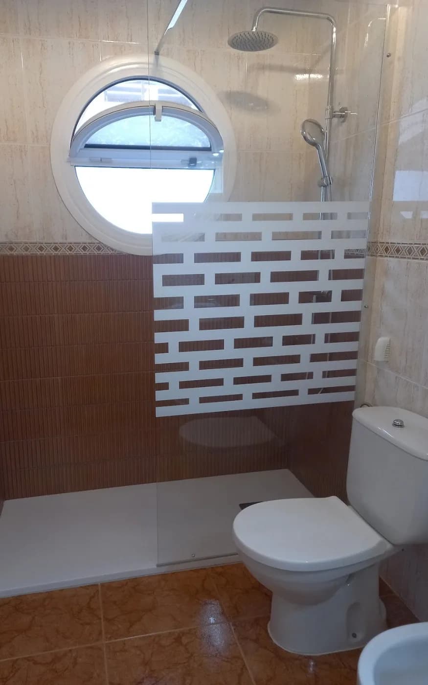Completed shower with glass screen, overhead shower and handheld fitting above the white tray.