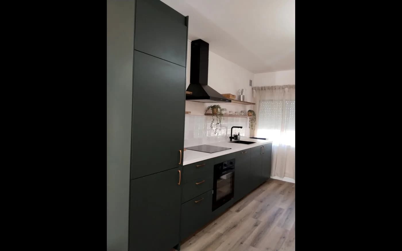 Completed kitchen with dark matte cabinetry, light worktops and wood-effect flooring.