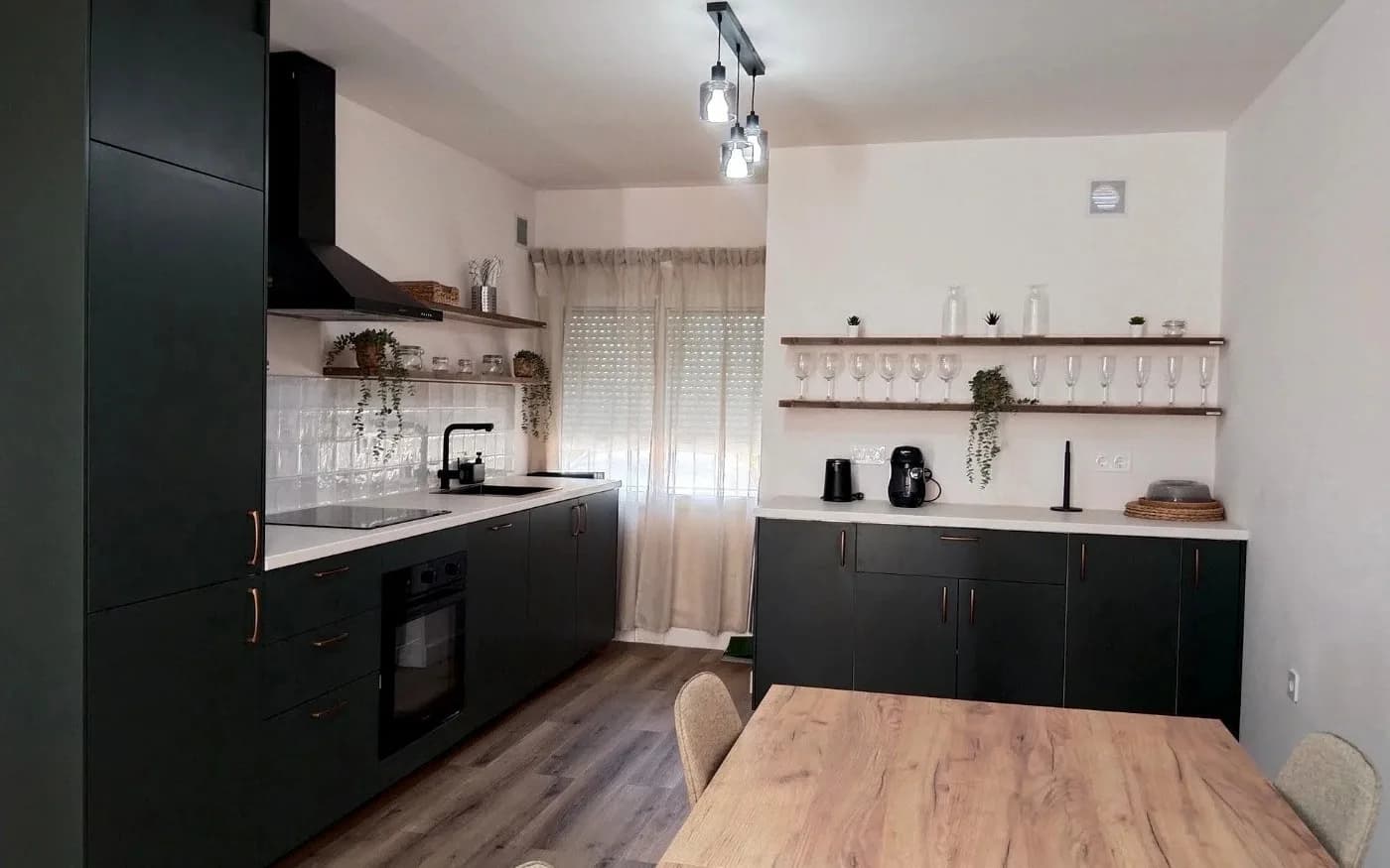 Renovated kitchen and dining area with dark matte cabinetry, light worktops and open shelving.